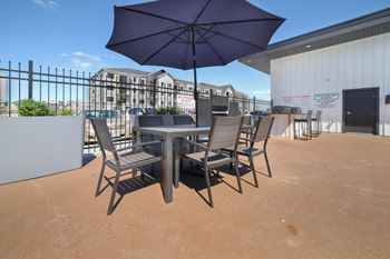 A table with chairs and an umbrella is set up on a patio.